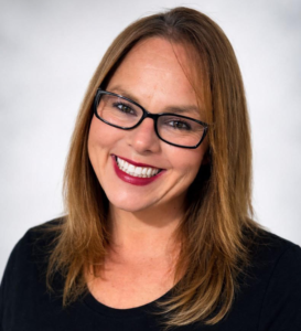 Christi Wier, Vicepresidenta de Desarrollo de Negocios en Chroma Early Learning Academy, sonriendo con gafas y una camiseta negra.