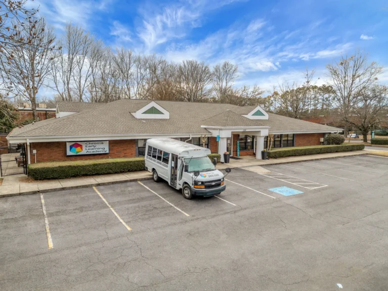 Chroma Early Learning Academy building with a shuttle bus parked outside, showcasing daycare and preschool services in Milton, GA.