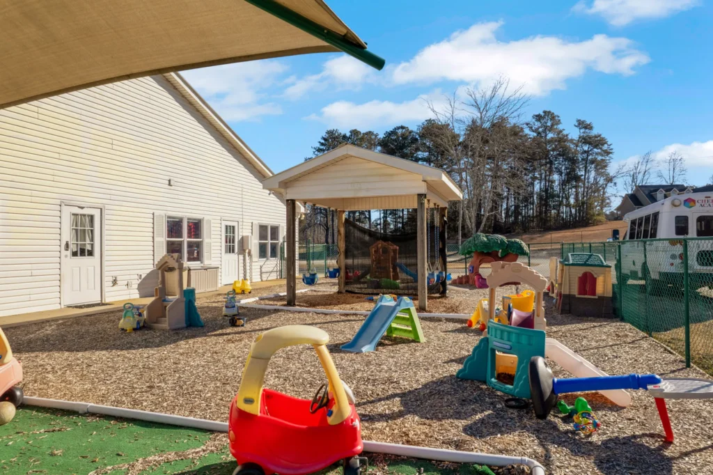 Playground area at Cherokee Academy featuring colorful play structures, toys, and shaded spaces for children in a safe, nurturing environment.