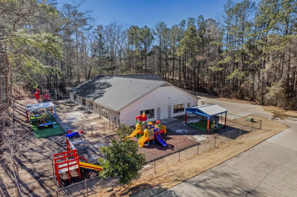 West Cobb Campus of Chroma Early Learning Academy featuring playground equipment, outdoor play area, and educational facility surrounded by trees in Marietta, GA.