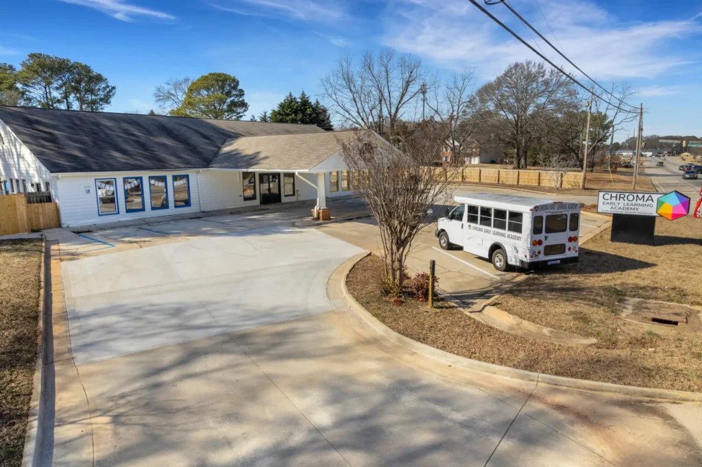 Chroma Early Learning Academy Ellenwood campus exterior with secure entry, white school bus, and colorful signage, emphasizing safety and accessibility for families.