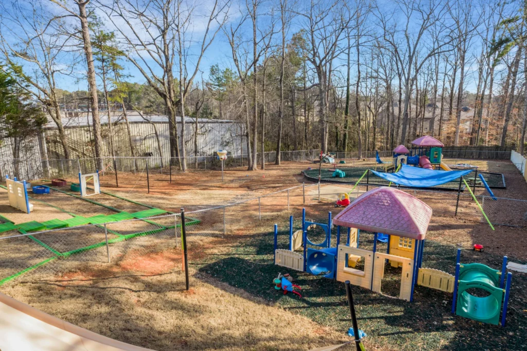 Playground area at Chroma Early Learning Academy's Lilburn Campus featuring colorful play structures, open space, and surrounding trees, emphasizing a safe and engaging environment for children.