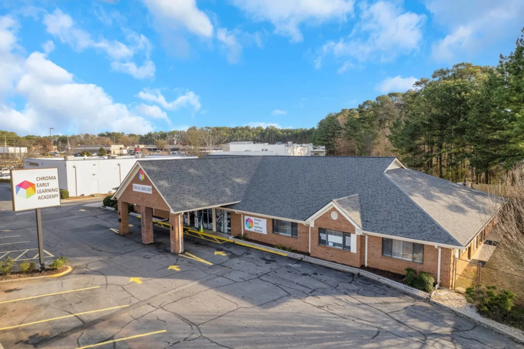 Chroma Early Learning Academy building in Lawrenceville, GA, featuring a welcoming entrance and signage, surrounded by a parking lot and trees under a blue sky.