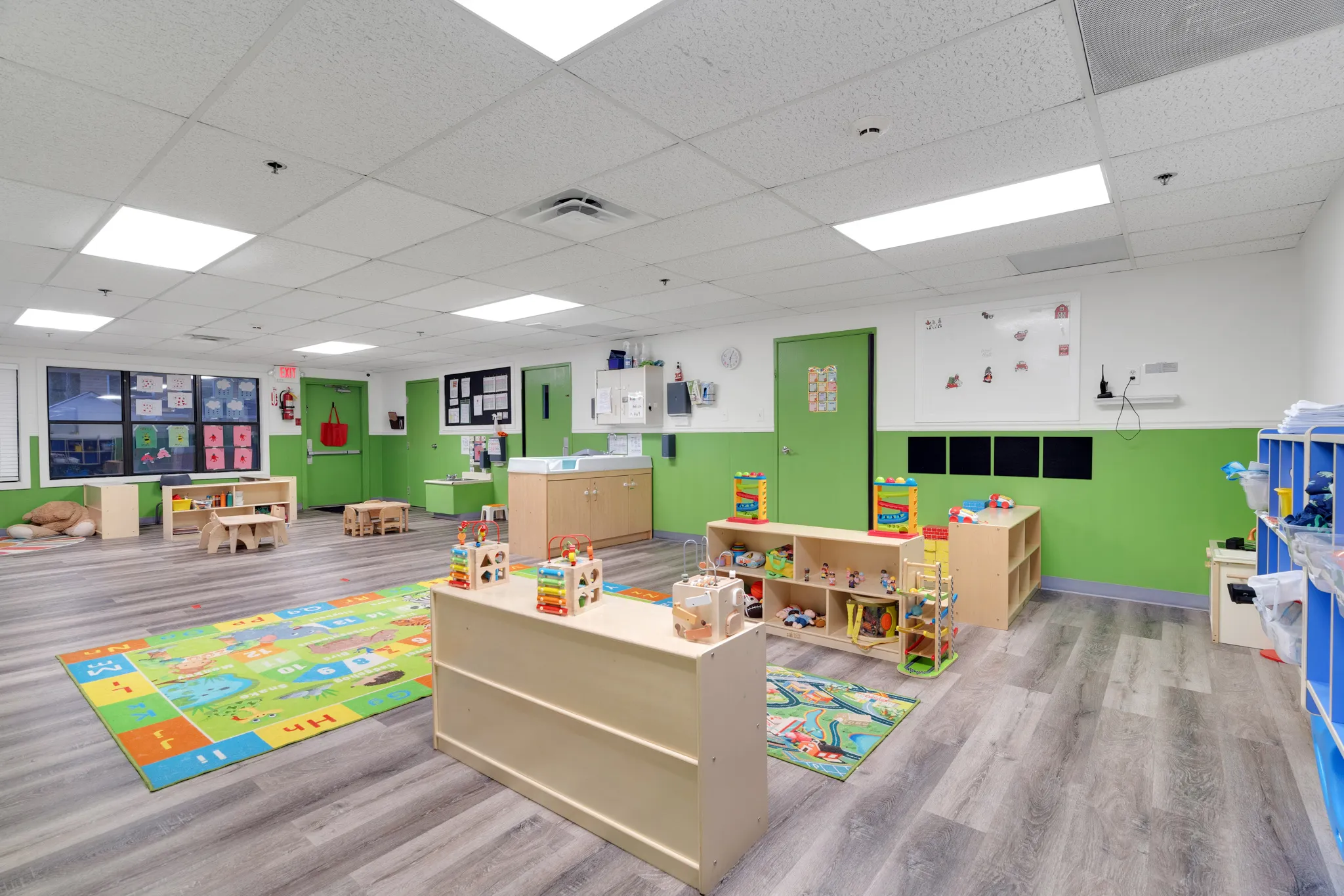 Brightly lit preschool classroom at Chroma Early Learning Academy in Dahlonega, featuring colorful educational toys, a patterned play rug, and green walls, designed for early childhood learning and play.