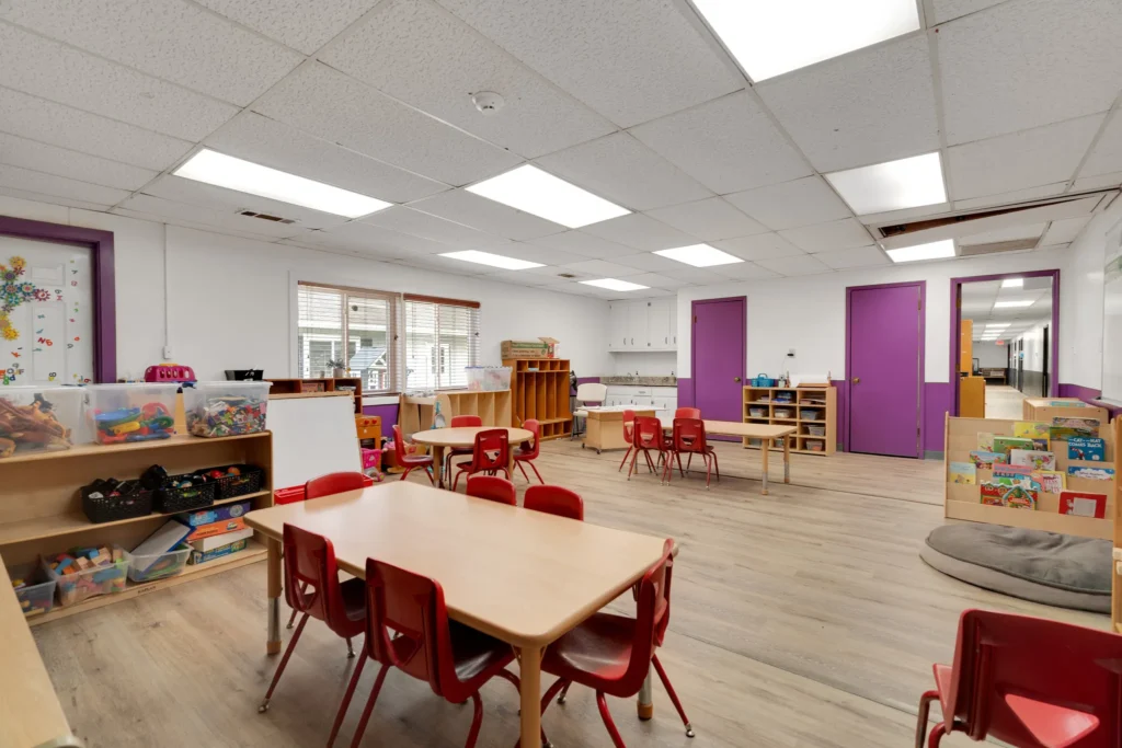 Classroom setting at Chroma Early Learning Academy, featuring red chairs, wooden tables, and colorful educational materials, emphasizing a nurturing environment for children's growth and creativity.