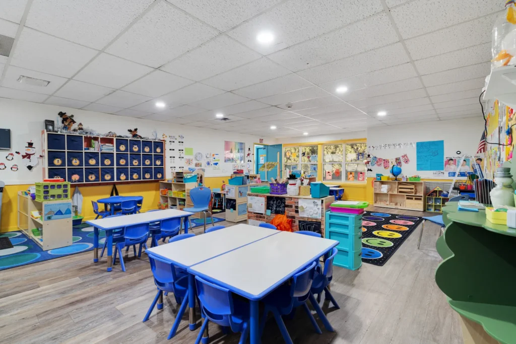 Brightly colored classroom at Chroma Early Learning Academy featuring blue tables and chairs, educational materials, and creative decorations, showcasing a nurturing environment for early childhood education in Marietta, GA.