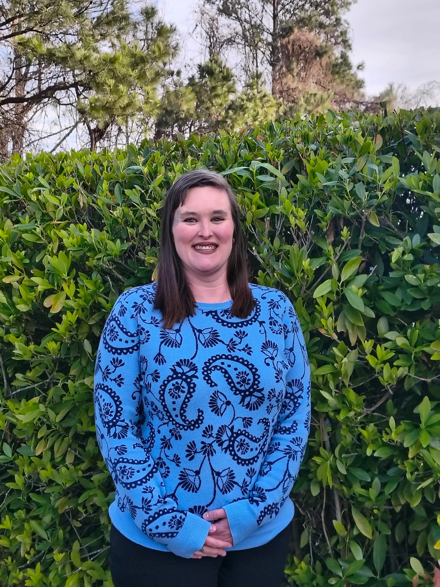 Meghan McNeil, Campus Director of Chroma Early Learning Academy, smiling in front of lush greenery, representing a welcoming educational environment.