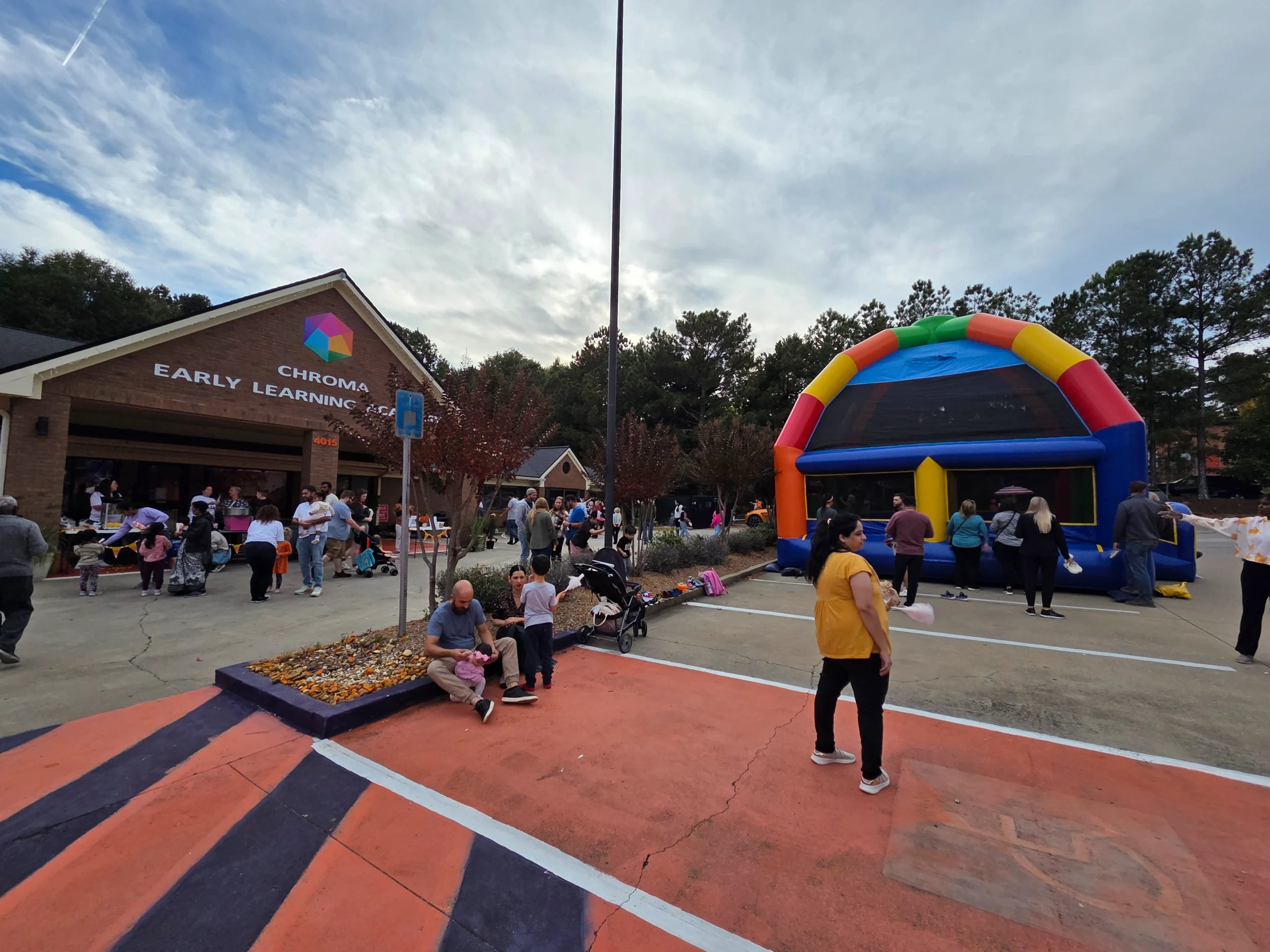 Chroma Early Learning Academy event with families gathered outside, colorful bounce house, autumn atmosphere, children playing, and community engagement.