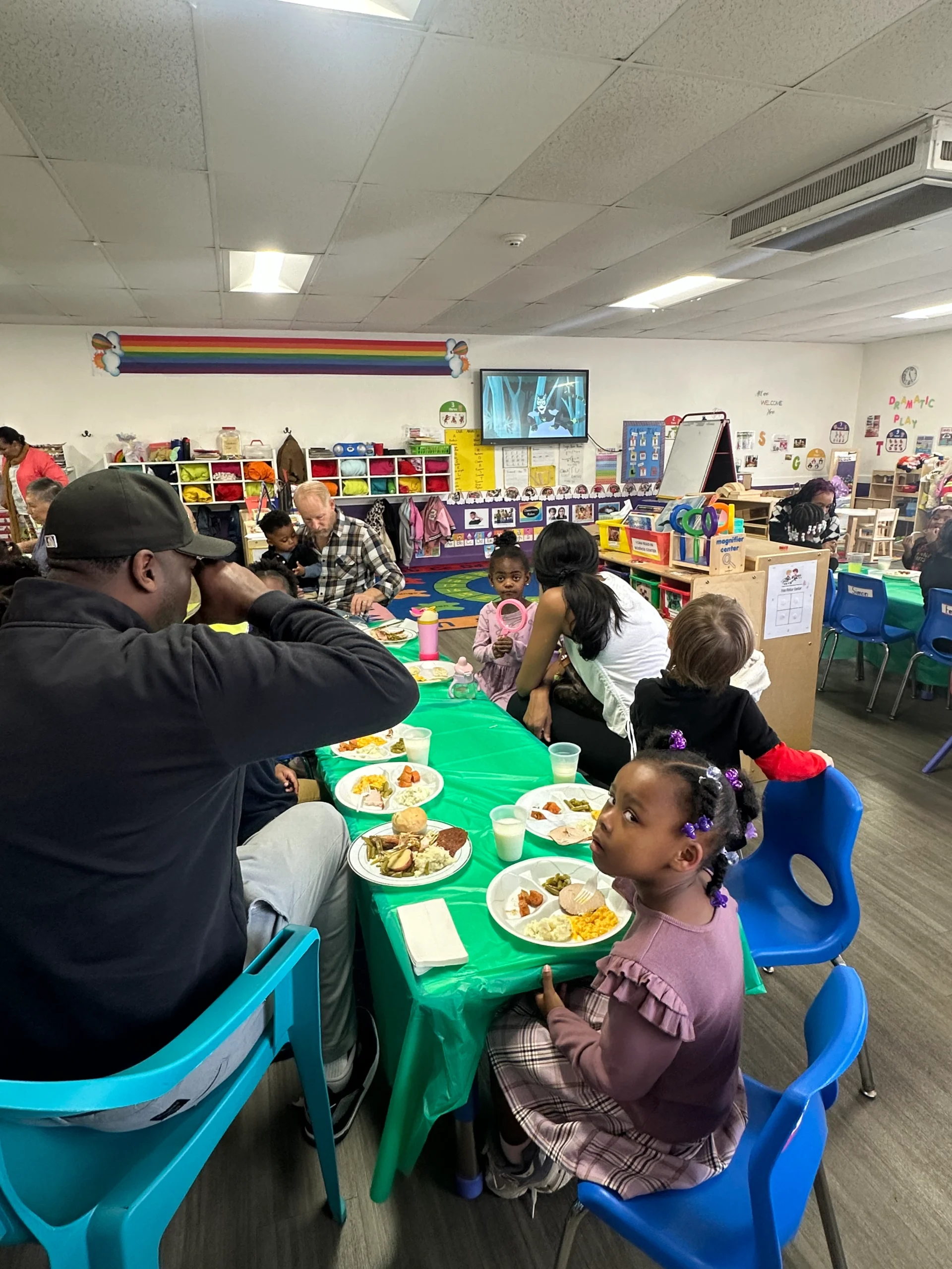Families enjoying a meal together in a colorful classroom setting at Chroma Early Learning Academy, highlighting community and engagement during a family event.