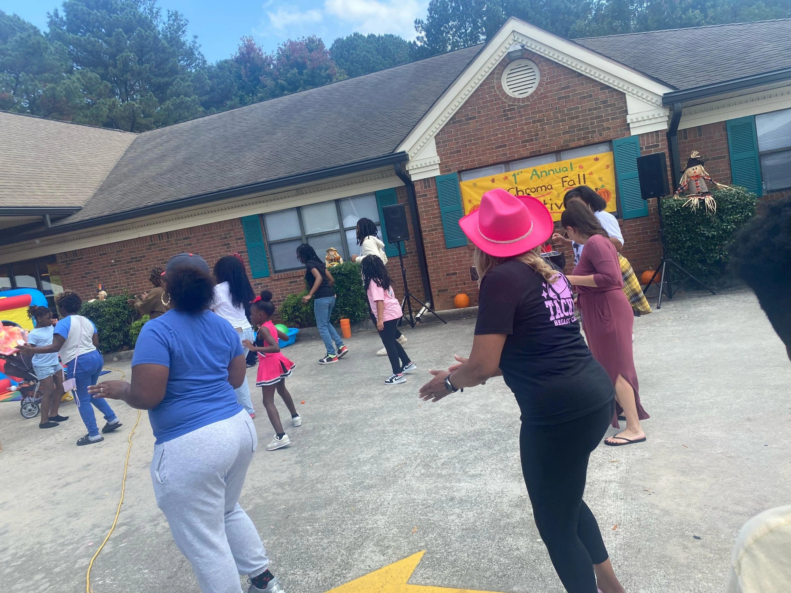 Families participating in the 1st Annual Chroma Fall Festival, enjoying activities and dancing outdoors, with a festive banner and decorations in the background.
